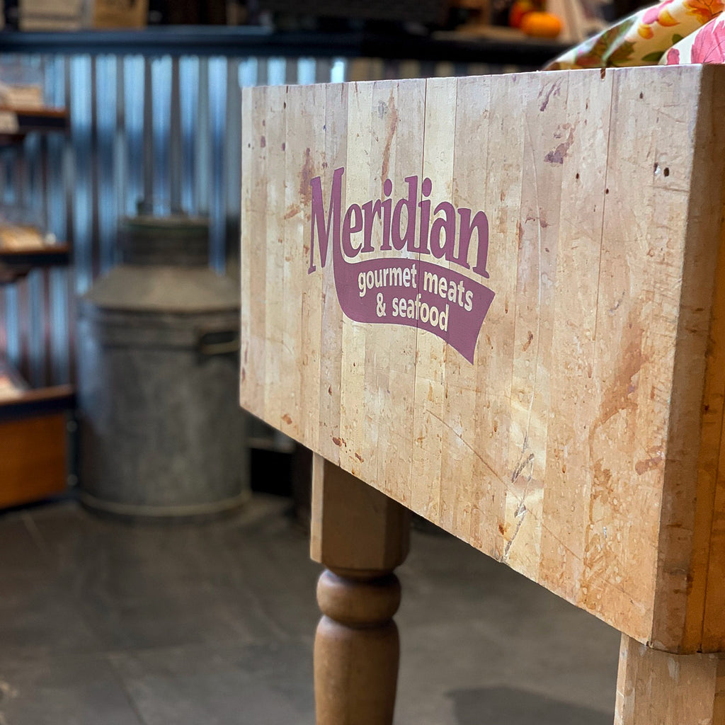 A close up of a traditional butchers block with a Meridian logo painted on the side. 