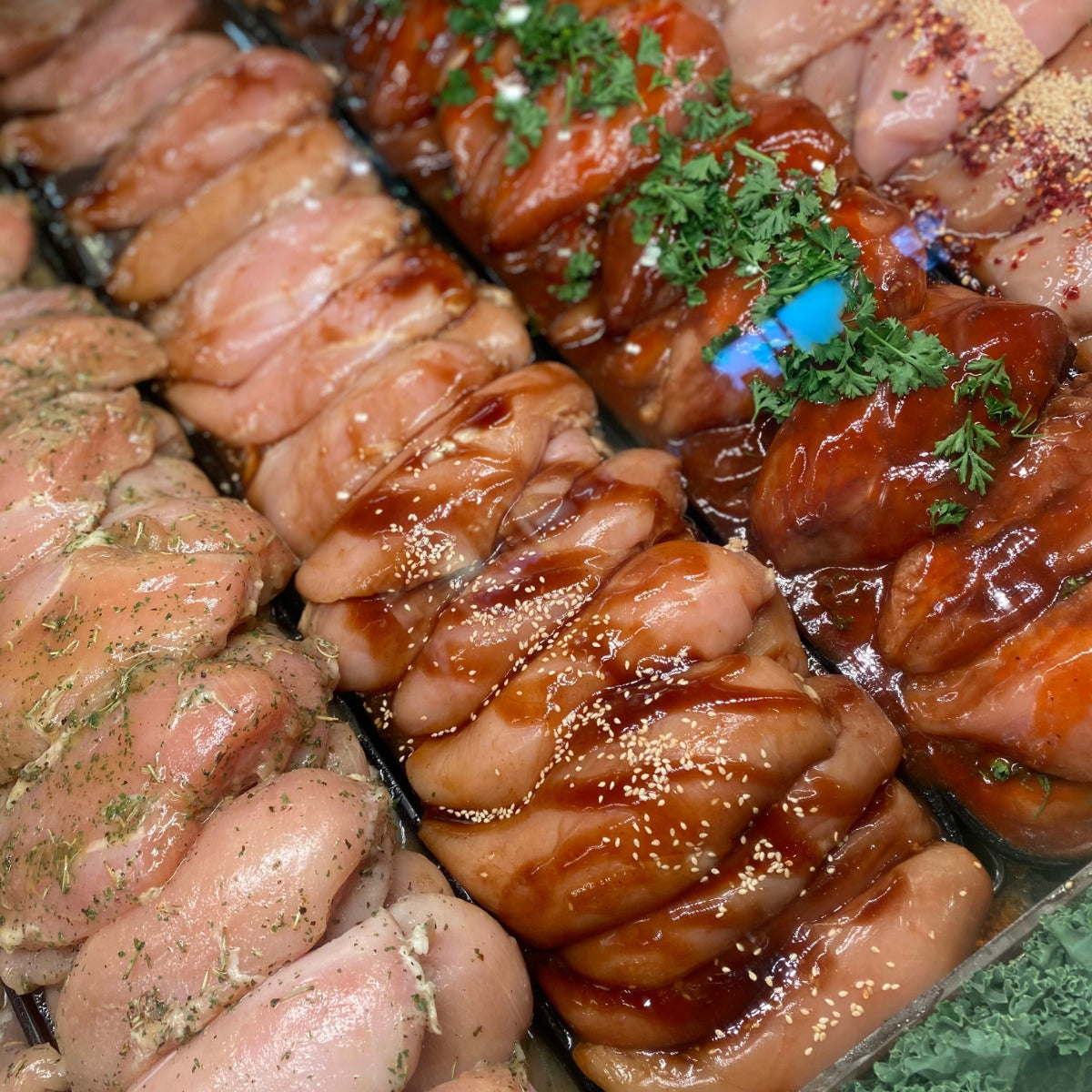 Maple Bourbon chicken breasts garnished in parsley next to different flavoured chicken breasts.