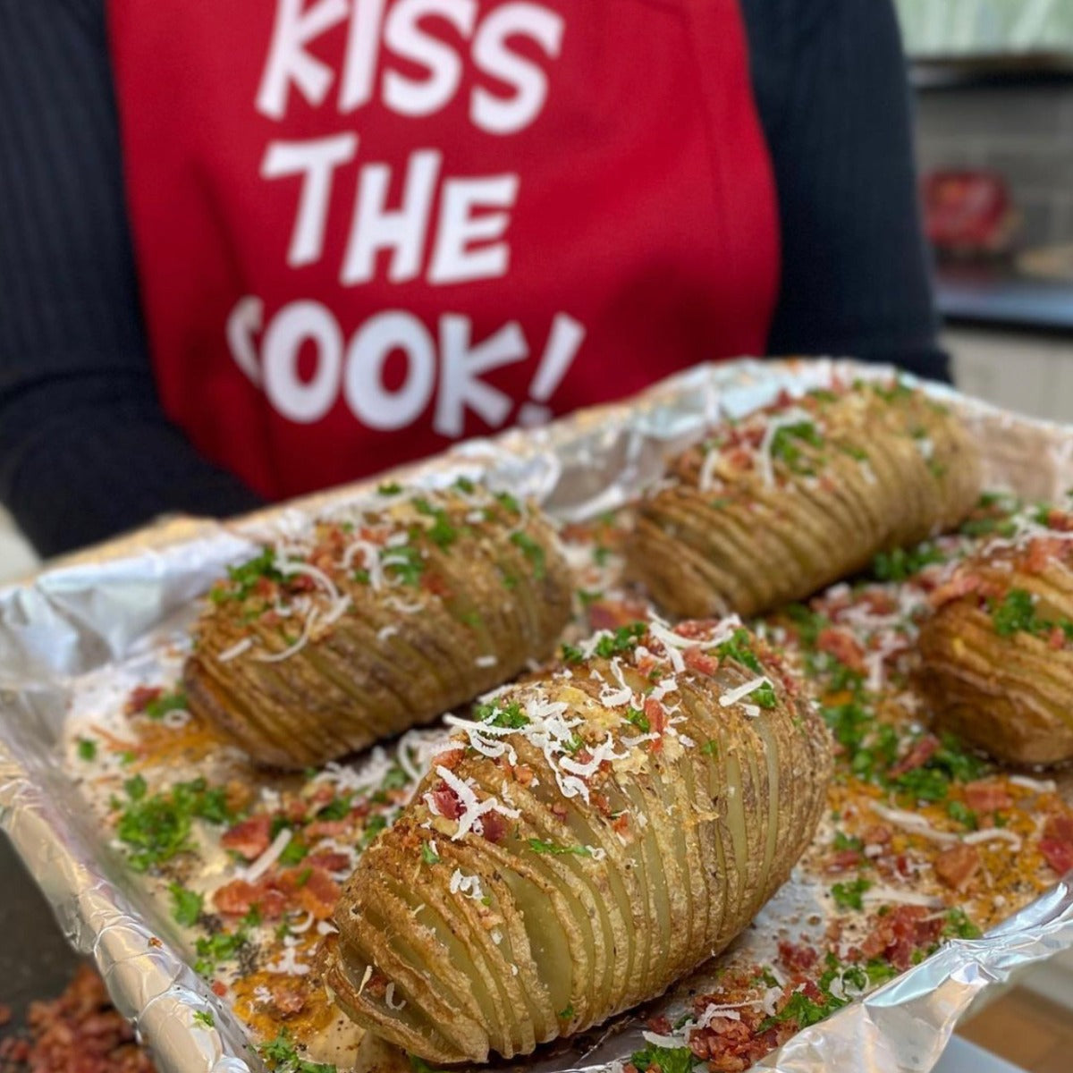 Four baked russet potatoes sliced on a pan and topped with bacon