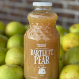 Meridian Farm Market Bartlett Juice 946 ml in front of Bartlett pears and a brick wall. 