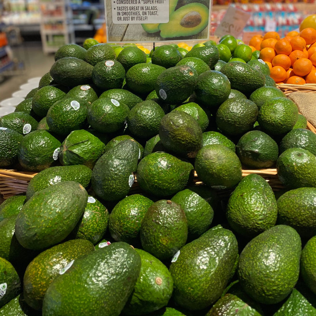 A mound of organic avocados in a wicker box on display inside a Meridian Farm Market.
