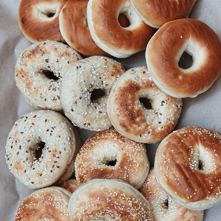 16 grain bagels sliced opened and place next to an assortment of bagels flavours. 
