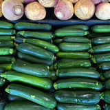 Rows of fresh zucchini displayed next rutabagas.