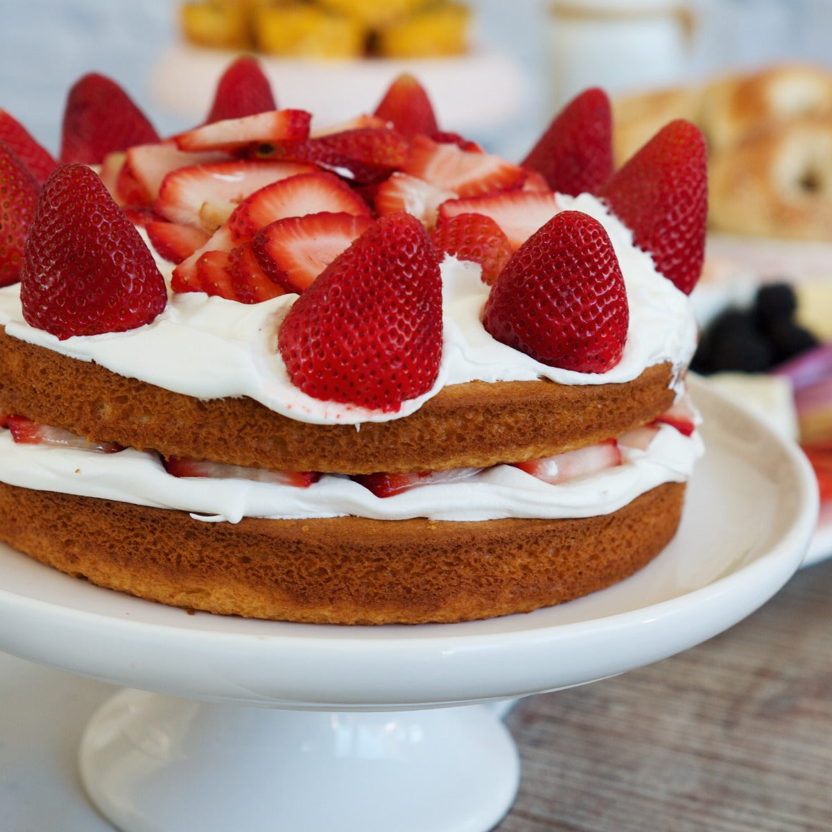 A cake decorated and filled with frosting and fresh sliced strawberries.