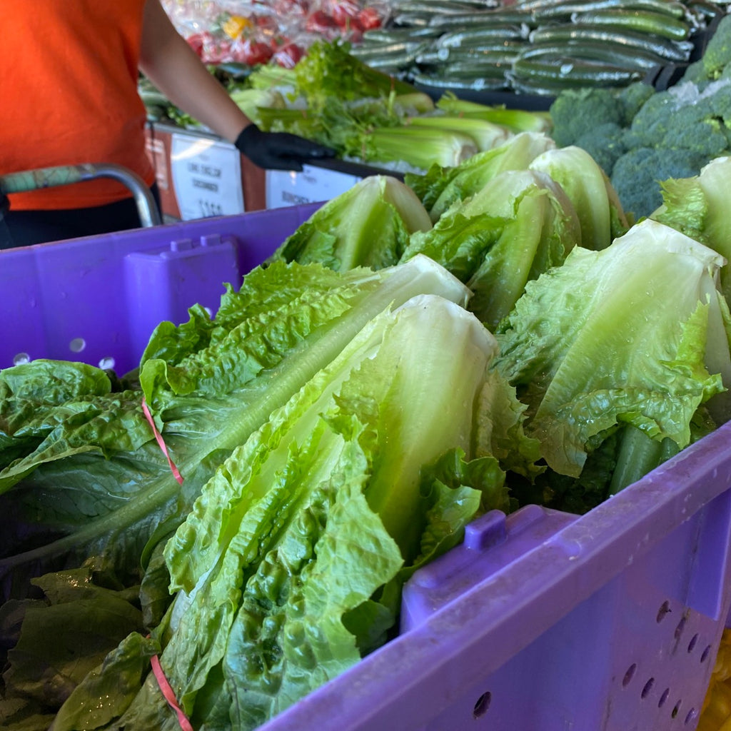 Heads of Romaine Lettuce in a large purple tray displayed in front of Meridian Farm Market