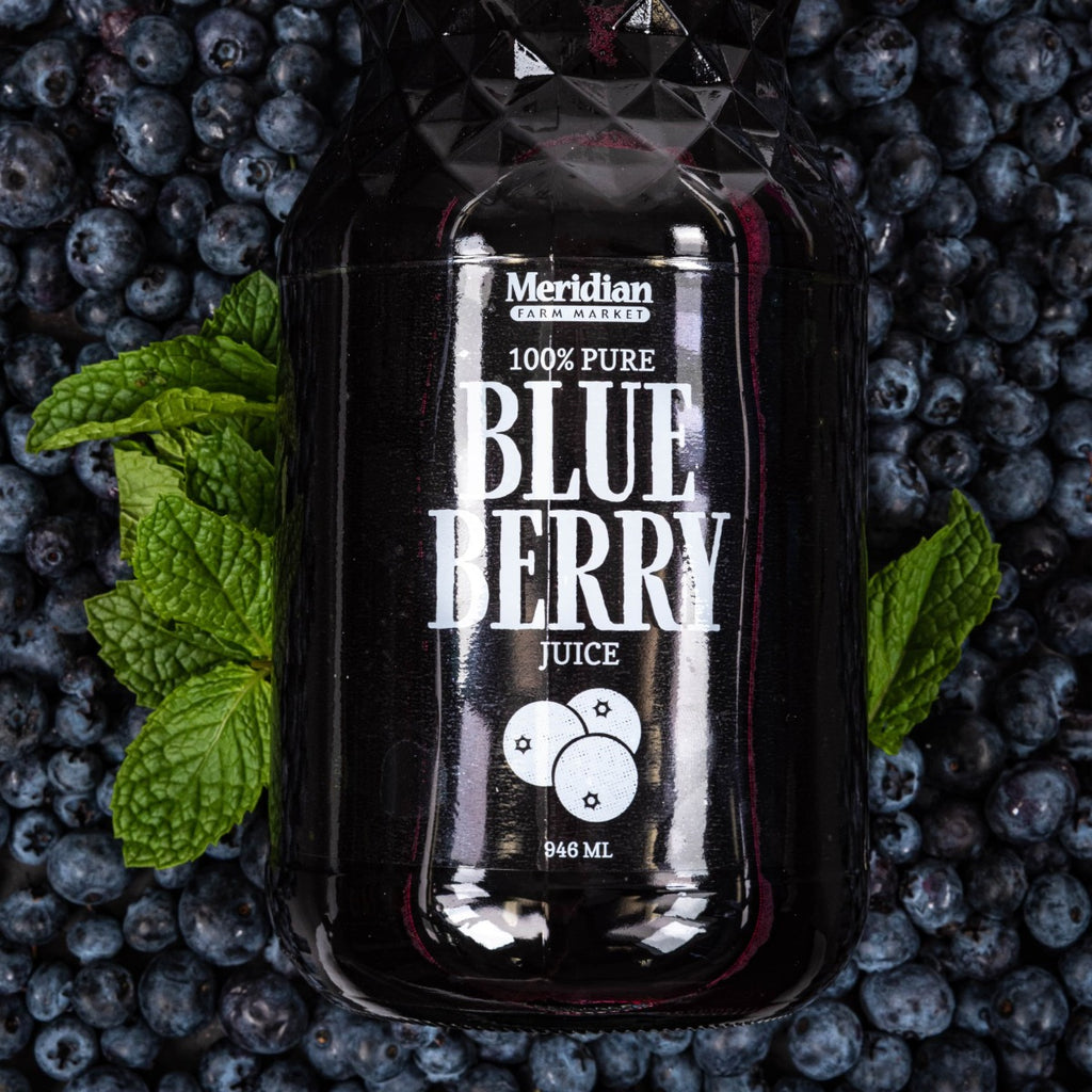 Meridian Farm Market Blue Berry Juice 946 ml laid upon a mound of blue berries.